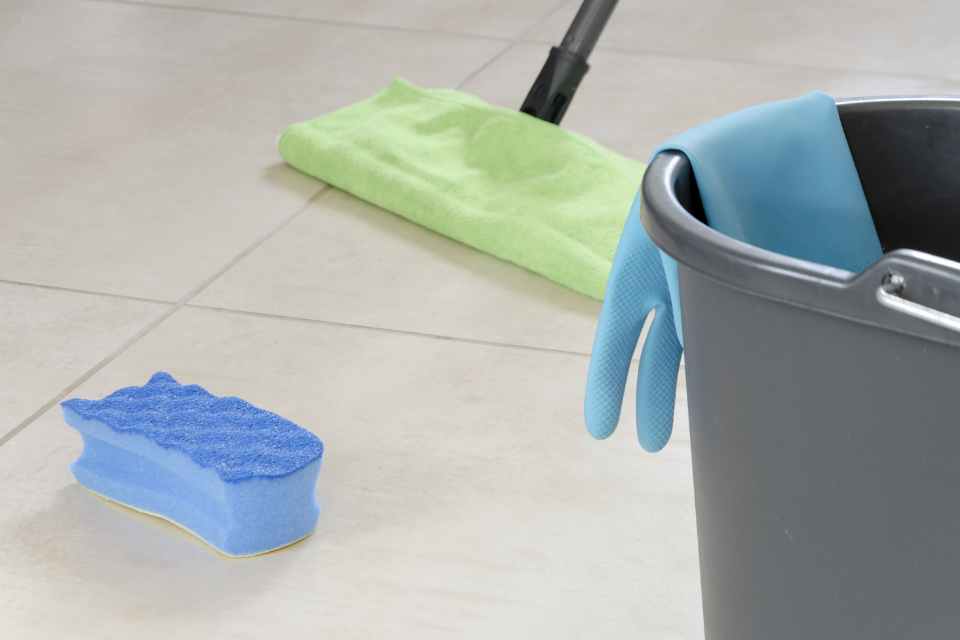 dry mop, sponge and bucket cleaning supplies on tile floor